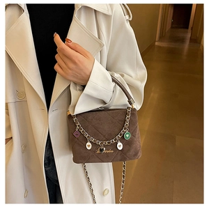 Detail of a dark brown quilted suede handbag with colorful heart charms and chain strap