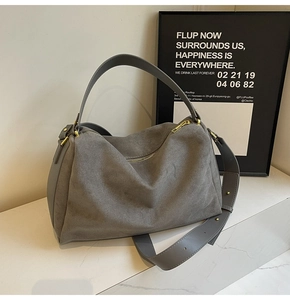 Detailed close-up of grey suede baguette bag with leather strap and golden hardware