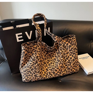 Close-up of leopard print canvas tote bag on leather sofa with lifestyle accessories
