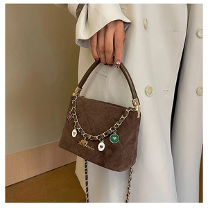 Close-up of brown quilted suede handbag with heart pendants and gold chain detail