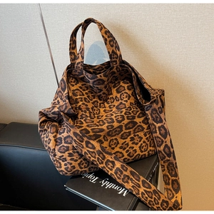 Detail of large leopard print tote bag with wide shoulder strap on a black sofa