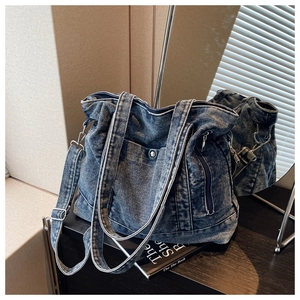 Detail of blue denim tote bag with metal snap pocket and adjustable crossbody strap