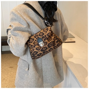 Detail view of a leopard print crossbody bag with silver hardware on a textured grey coat