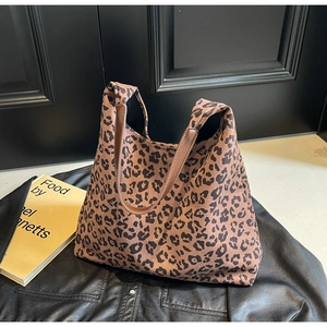 Vue détaillée du sac cabas imprimé léopard avec anses en cuir marron sur cuir noir