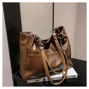 Detail view of large brown faux leather tote bag with silver ring hardware and side pocket