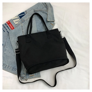 Detailed top view of black canvas tote bag with adjustable straps and denim background