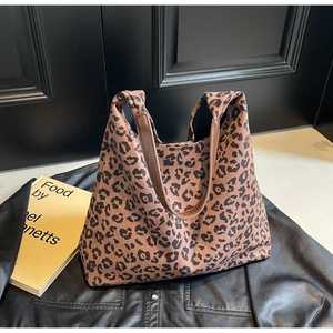 Détail d'un cabas en toile à imprimé léopard avec des poignées en cuir sur une veste en cuir
