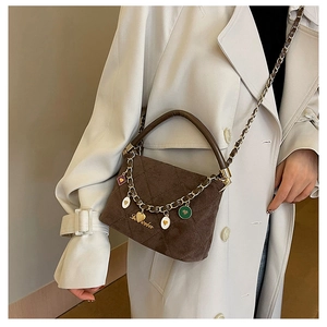 Macro shot of brown suede handbag with Labubu logo and colorful heart charms on chain
