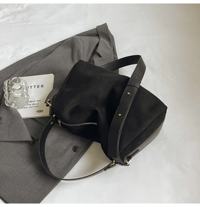 Detailed macro view of black suede bag with gold zipper and stylish metal rivets
