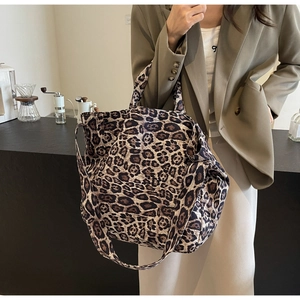Detail of leopard print tote bag with dual handles and shoulder strap in lifestyle setting