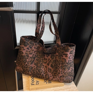 Detail view of large leopard print tote bag made of textured canvas on marble surface
