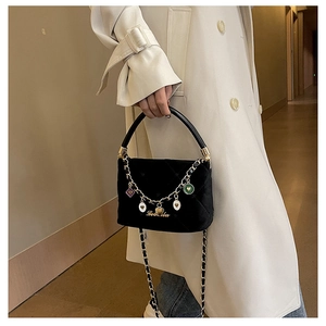 Close-up of black velvet mini handbag with golden heart charms and chain strap