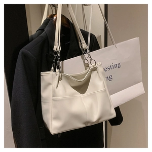 Detail of soft cream tote bag with dual shoulder straps and metallic chain elements
