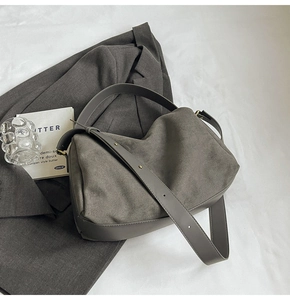 Detail of dark grey suede shoulder bag with smooth leather trim and metal rivets