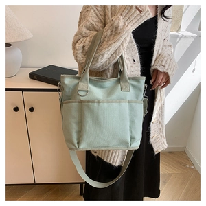 Detail of mint green canvas tote bag with multi-pocket design and adjustable shoulder strap