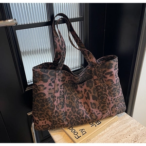 Detail of leopard print canvas tote bag featuring a front pocket and durable double straps