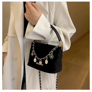 Close-up of black quilted velvet handbag with colorful heart charms and golden chain