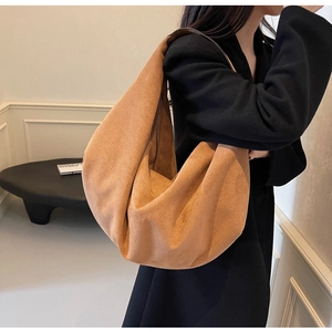 Close-up of caramel brown suede hobo bag styled with a professional black blazer for work
