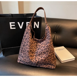 Vue détaillée du sac hobo à imprimé léopard avec bandoulière en cuir sur un canapé noir