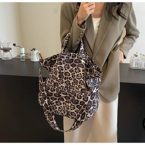 Detail of stylish leopard print tote bag with dual straps worn by a model in a suit