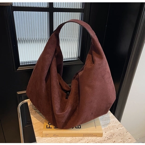 Detail of burgundy suede tote bag with wide strap on marble surface showing soft texture
