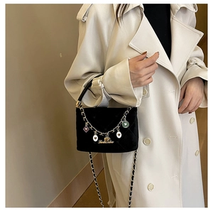 Detail showing black velvet crossbody bag with golden chain and colorful heart charms