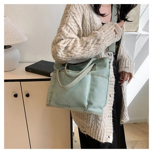 Detail of mint green canvas tote with functional front pockets and detachable strap