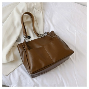 Detail of dark brown tote bag with silver chain straps and front pockets for daily commute