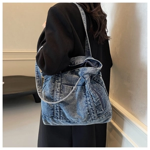 Detailed side view of the washed blue denim tote bag with visible fine stitching on shoulder