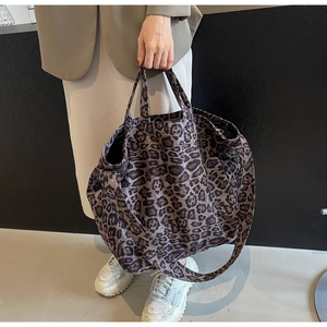 Detail of a large leopard print tote bag with double handles and long shoulder strap