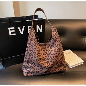 Détail du sac hobo vintage à imprimé léopard avec large bandoulière en cuir sur canapé