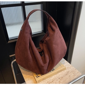 Macro detail of high-capacity burgundy suede hobo bag on elegant marble surface