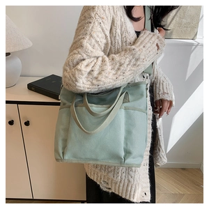Detail showing light green canvas tote bag with adjustable shoulder strap and pockets