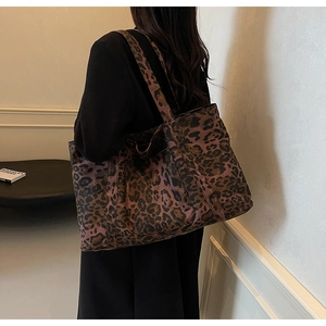Detailed side view of large leopard print tote bag worn on shoulder by model
