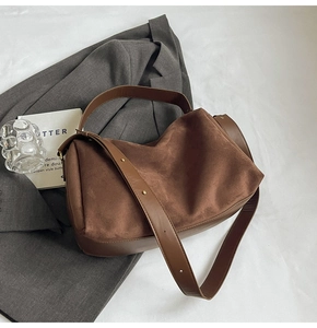 Brown suede bag detail showing matte texture and rivets on a minimalist shoulder strap