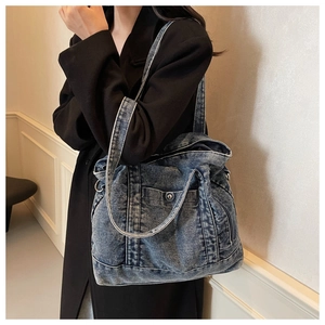 Detail shot of the washed blue denim tote bag showing functional side pockets and stitching