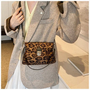 Detail shot of a vintage leopard print crossbody bag with metal buckle on a model