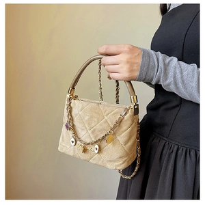 Detail view of quilted suede crossbody bag with gold heart charms on chain strap