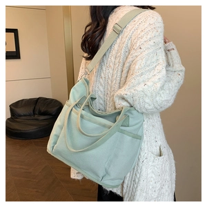 Detail of mint green canvas tote bag showing wide shoulder strap and side pocket