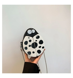 Detail of ladybug-shaped PU leather crossbody bag with lychee texture and bead chain