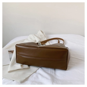 Detail view showing the wide base and neat stitching of the brown PU leather tote bag