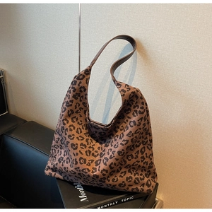 Détail du sac cabas imprimé léopard avec bandoulière en cuir posé sur un canapé