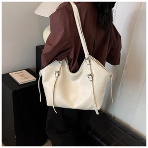 Close-up of cream leather tote bag featuring adjustable silver metal buckle on strap