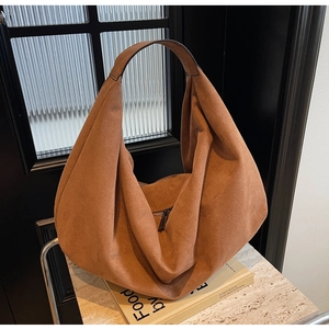Detail shot of a brown suede hobo bag with wide shoulder strap in a stylish home setting