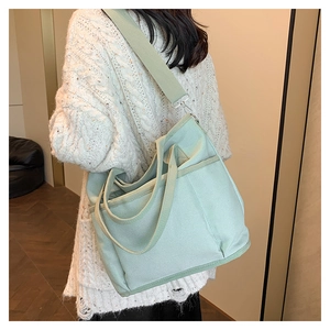 Detail of mint green canvas tote bag with side pocket and wide shoulder strap