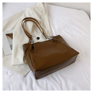 Detailed view of dark coffee tote bag with leather texture and silver chain strap details