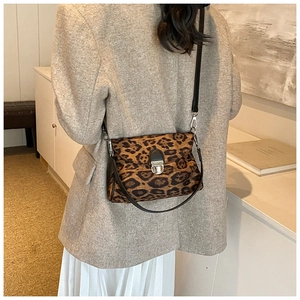Rear view of a model wearing a small leopard print crossbody bag with silver buckle