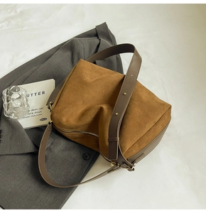 Detail of caramel suede hobo bag with adjustable leather strap on a grey blazer