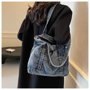 Macro detail of vintage denim tote bag showing metal zipper pocket and washed fabric