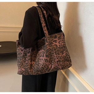 Model wearing a large leopard print tote bag showing the side view and spacious design
